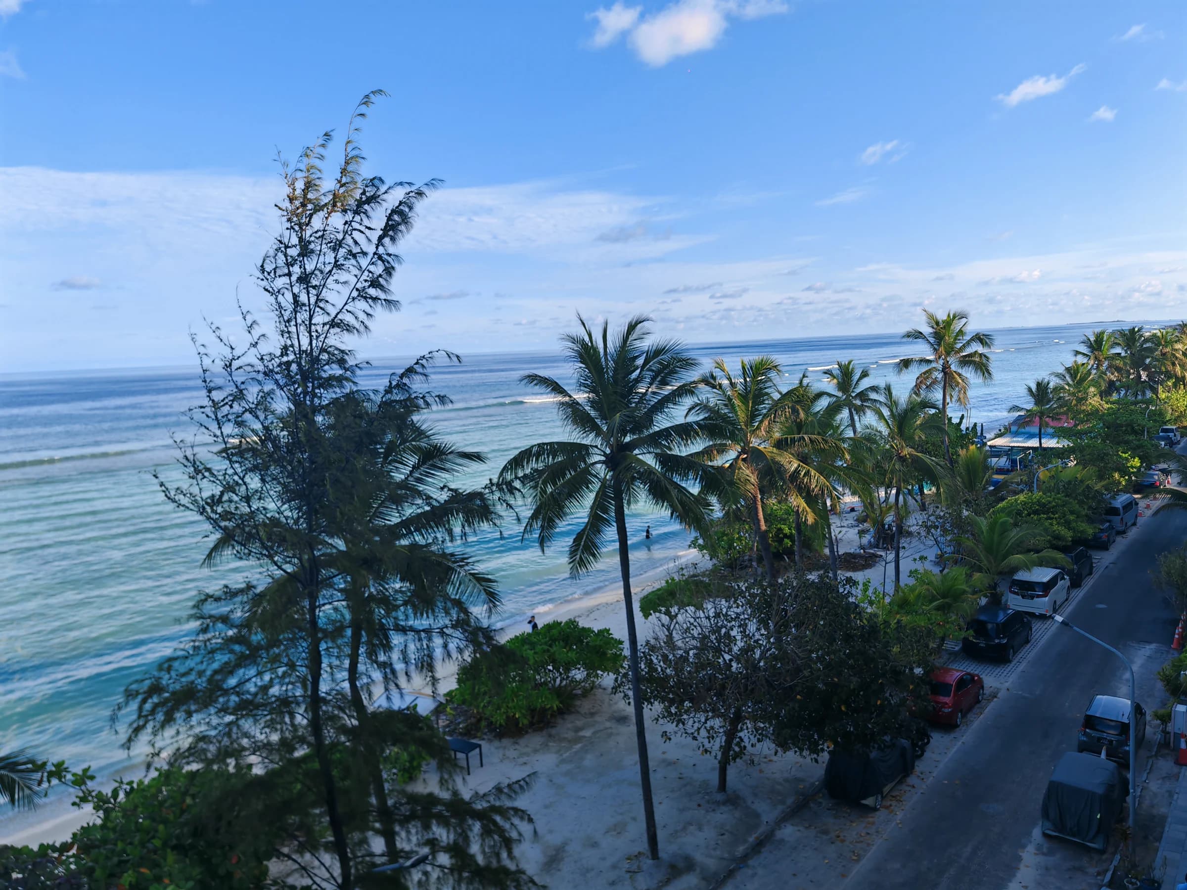 Palm trees above a quiet beach and blue ocean at Hulhumale