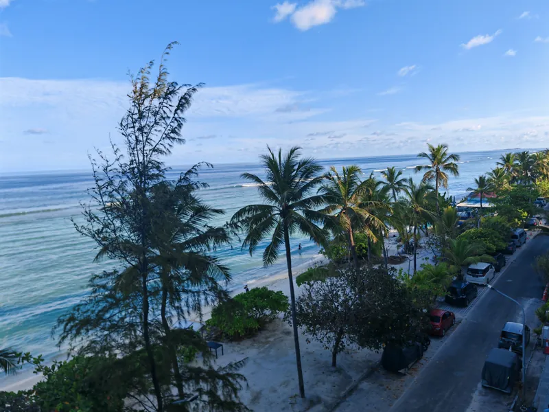 Palm trees above a quiet beach and blue ocean at Hulhumale