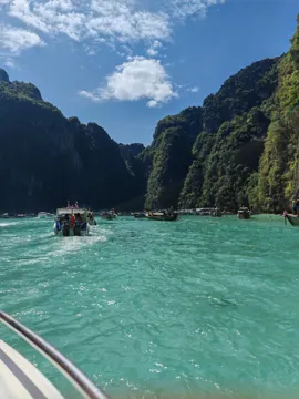 A boat crossing a bright turquoise lagoon between limestone cliffs