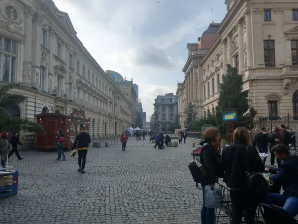 Cafés and pedestrians along a cobbled Bucharest street