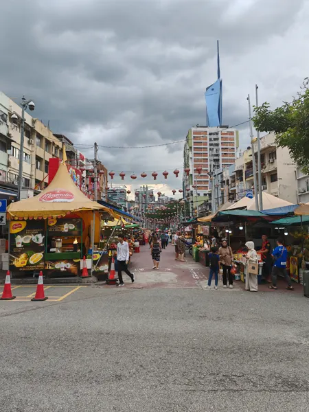 A lively Kuala Lumpur market street beneath modern towers