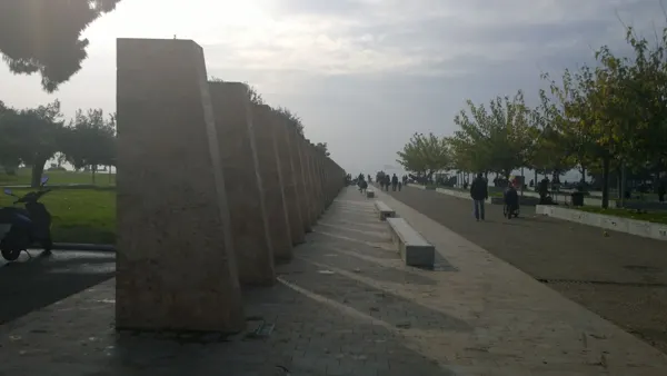 A long waterfront promenade lined with trees and stone panels
