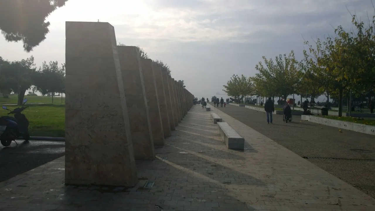 A long waterfront promenade lined with trees and stone panels