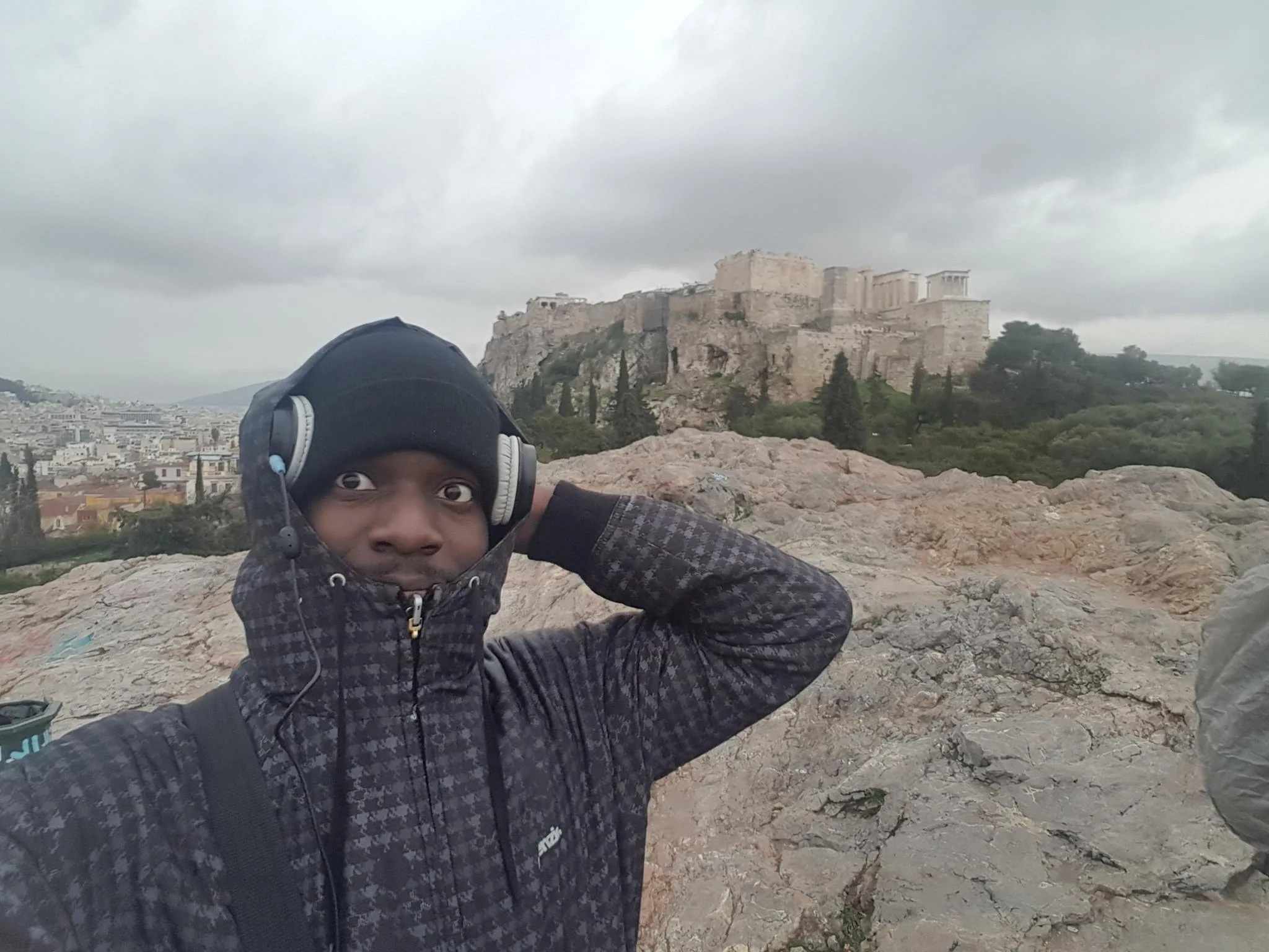 A traveller overlooking the Acropolis beneath a cloudy sky