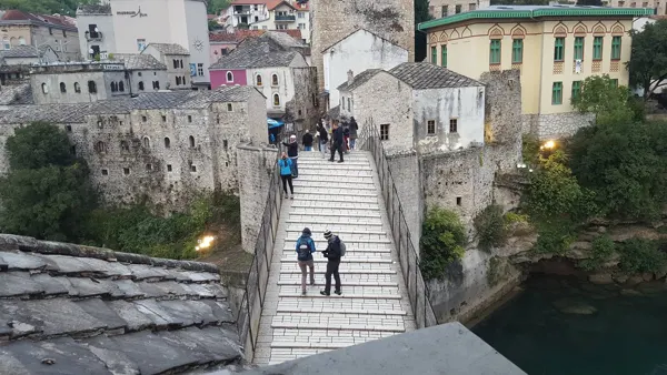 Visitors walking across the stone arch of Stari Most