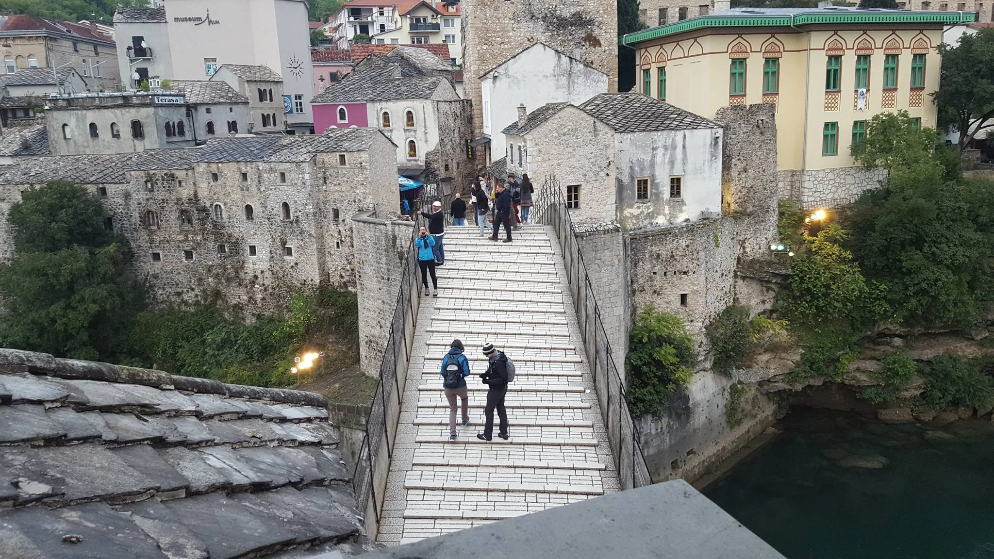 Visitors walking across the stone arch of Stari Most