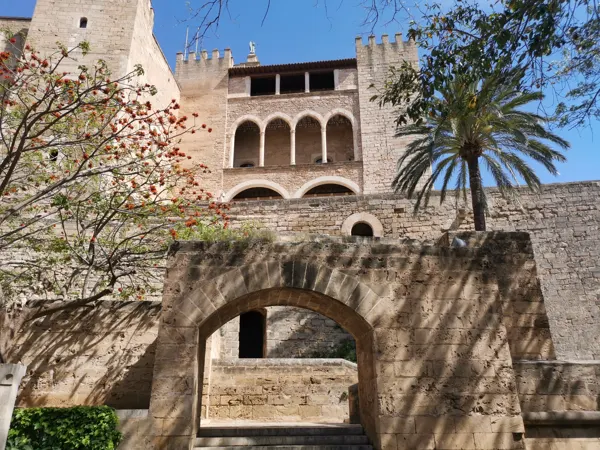 Stone arches and palms beside the Almudaina Palace in Palma