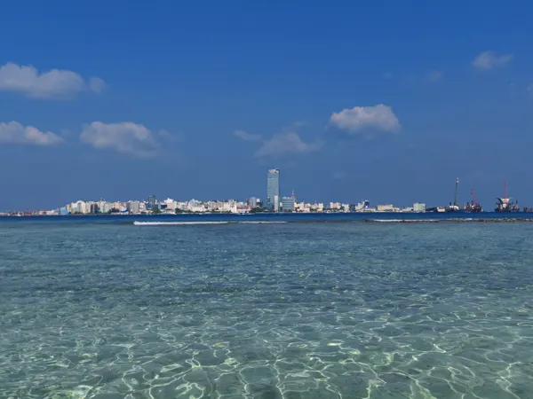Clear shallows off Villingili with the Malé skyline across the water