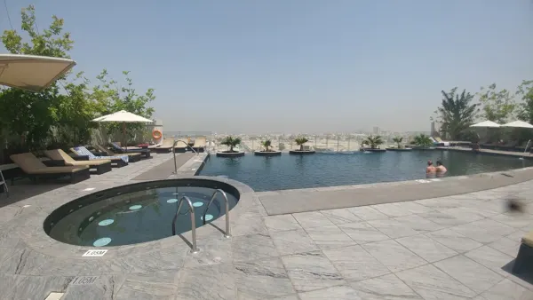 An outdoor pool and shaded loungers beneath a hazy sky