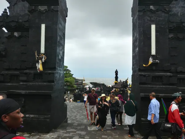 Visitors passing through a tall split-stone gateway