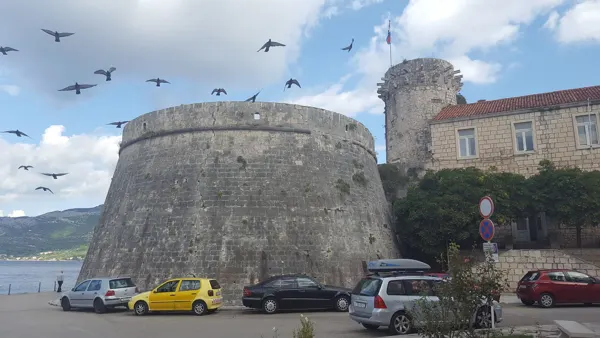 Birds flying above a round stone tower on the Croatian coast
