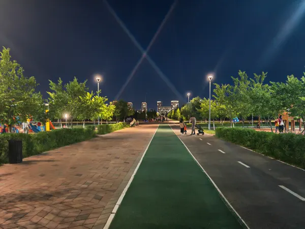 Lit walking and cycling paths through an Astana park at night