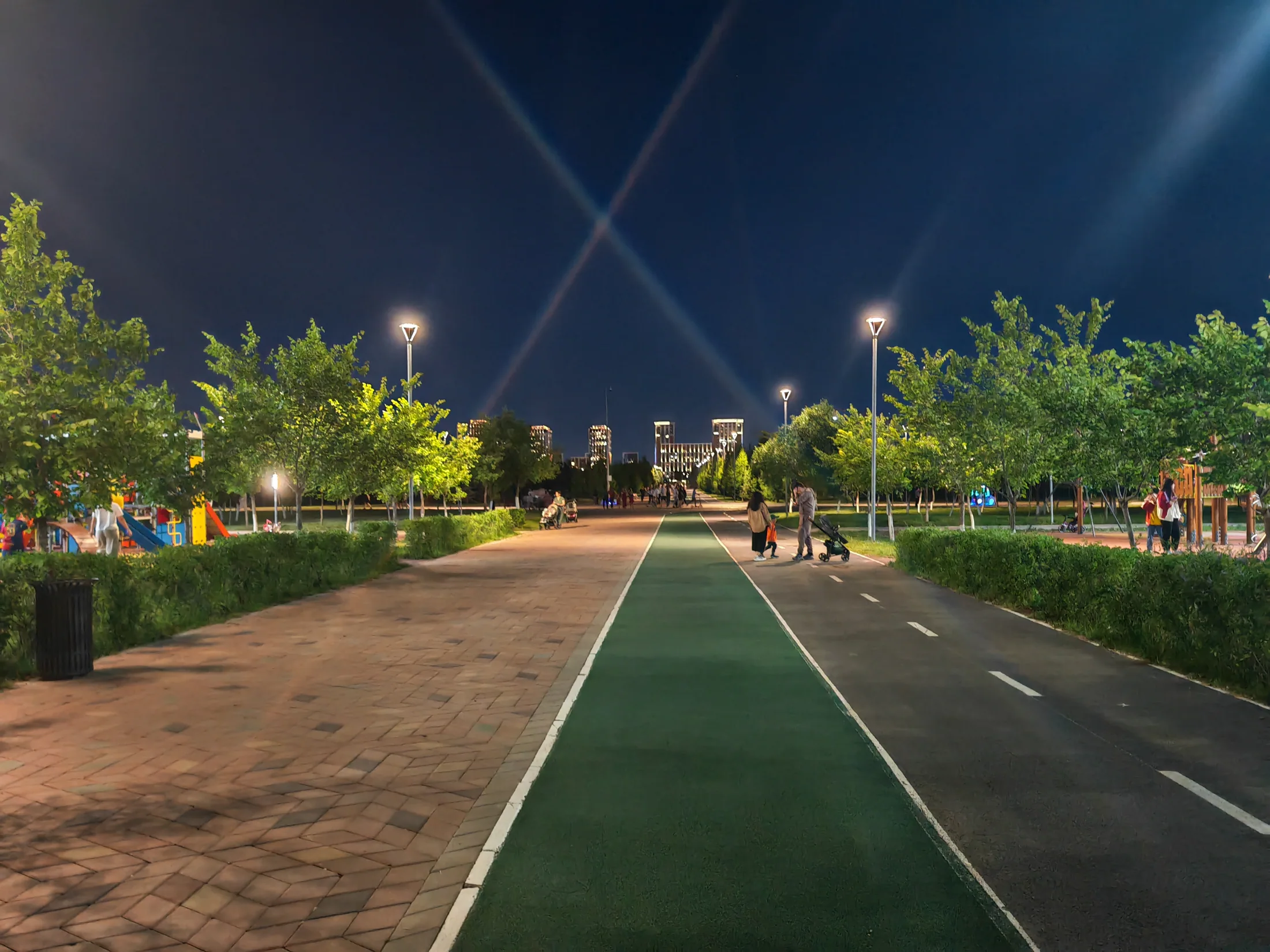 Lit walking and cycling paths through an Astana park at night