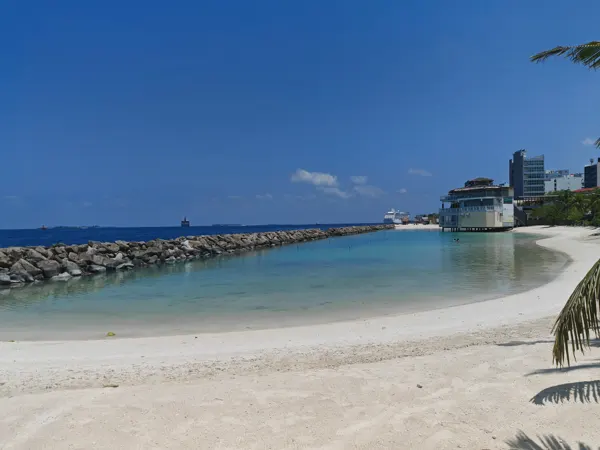 Clear water and a sheltered beach beside Malé’s sea wall