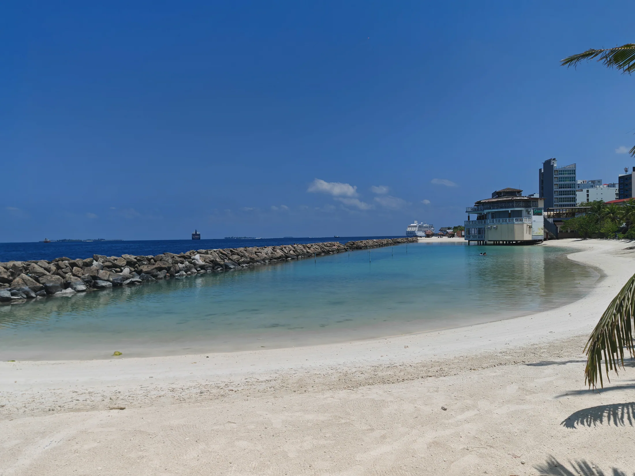 Clear water and a sheltered beach beside Malé’s sea wall