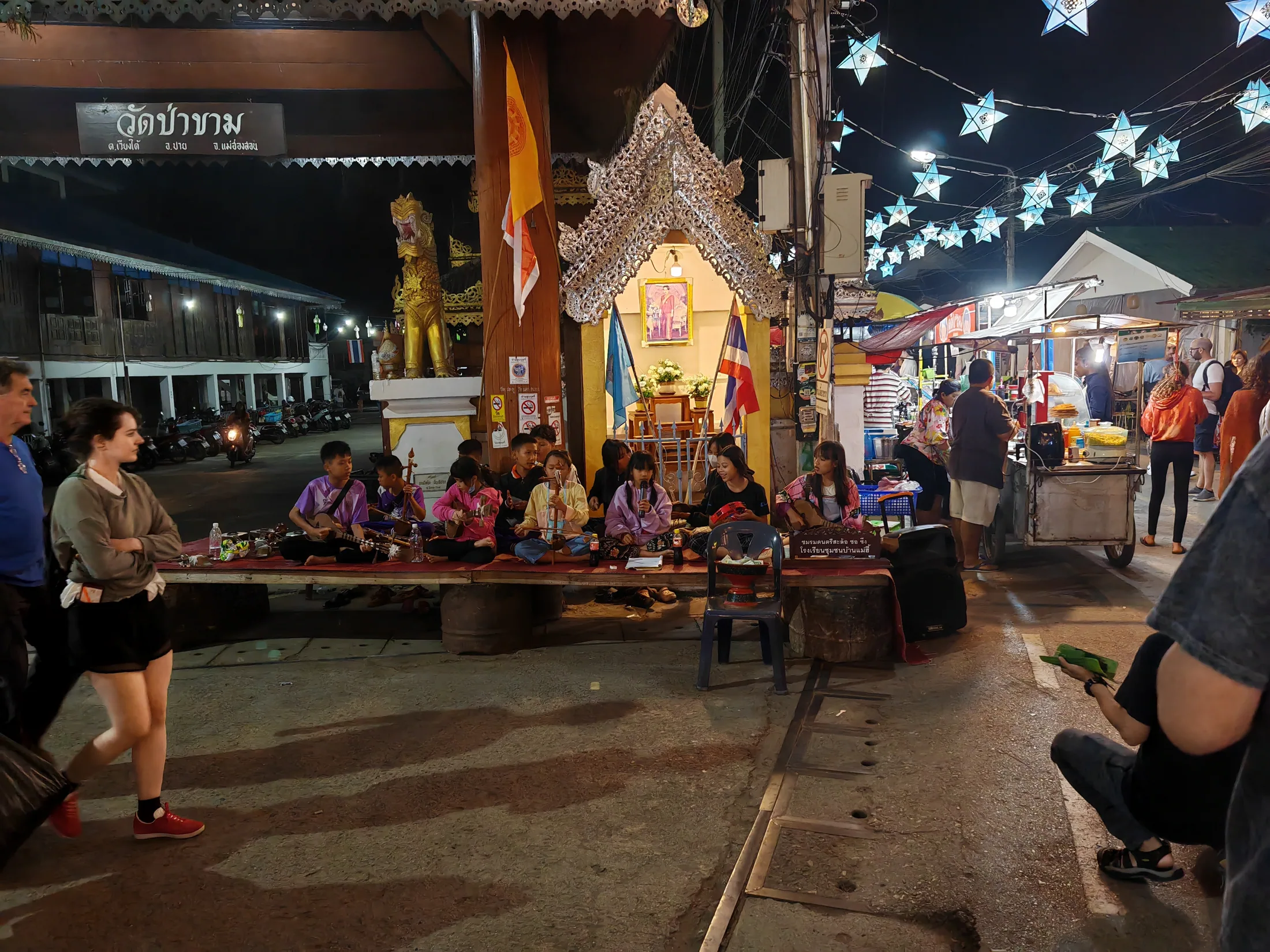 Musicians beside a decorated shrine at a Thai night market
