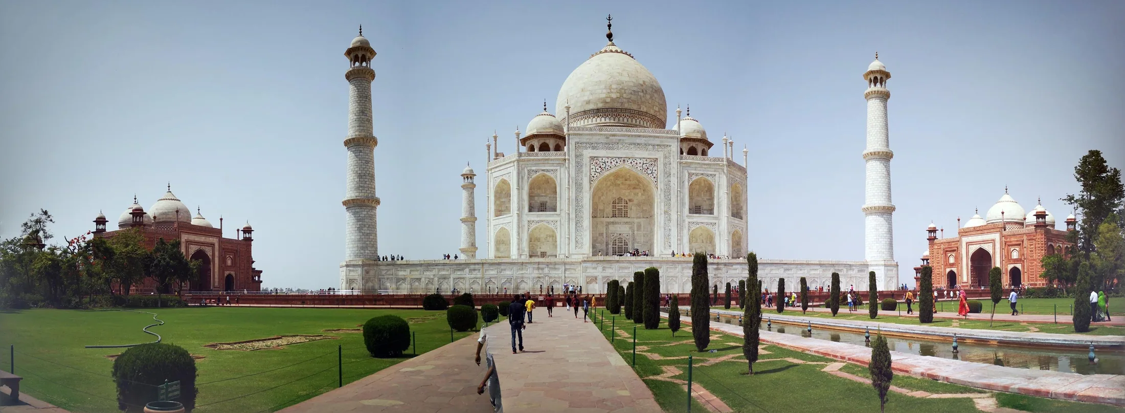 The Taj Mahal and gardens beneath a pale blue sky