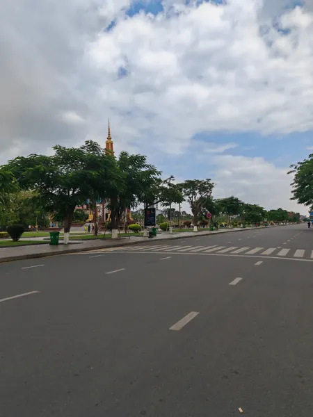 A broad boulevard and monument beneath clouds in Phnom Penh