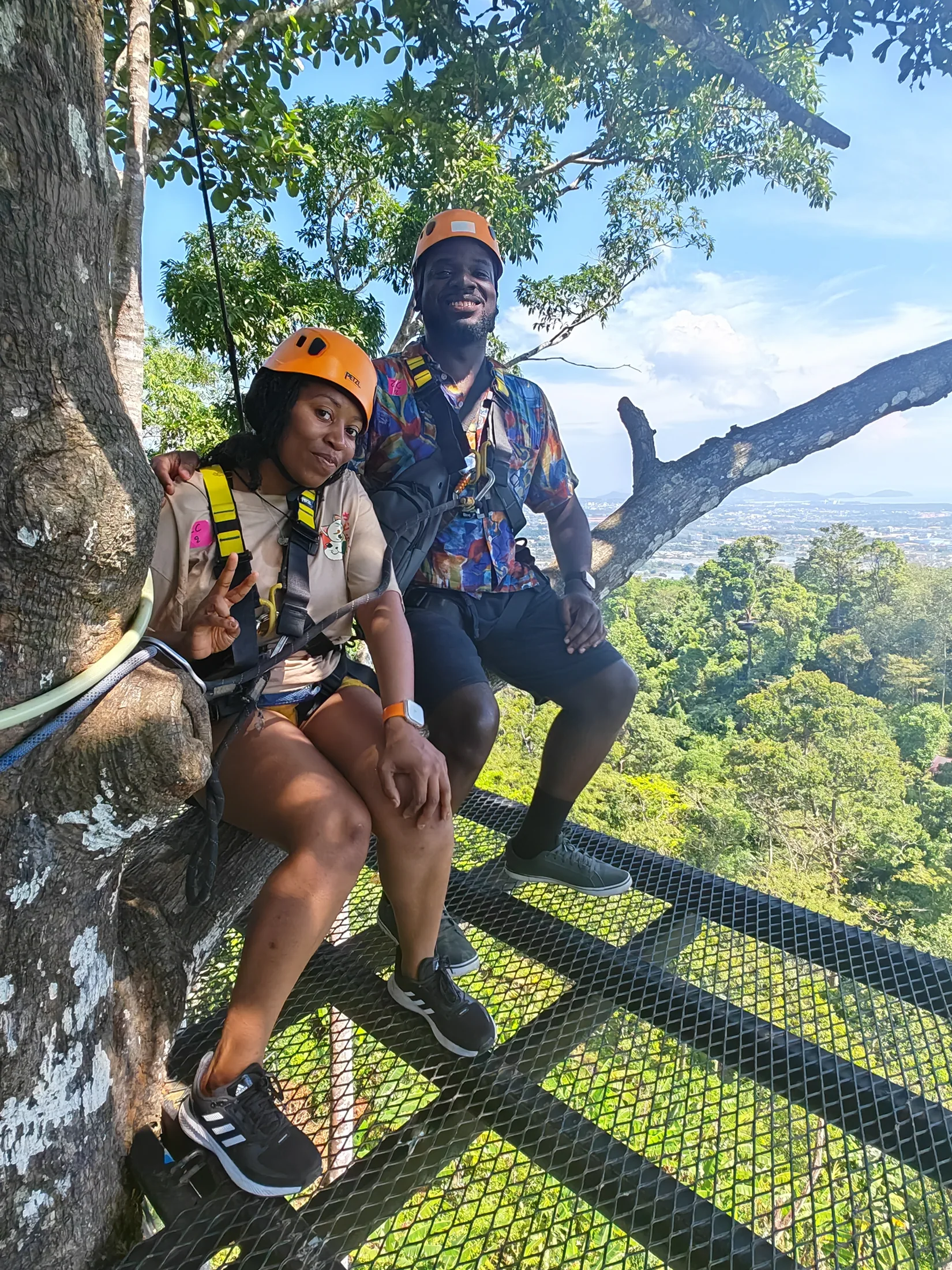 Two travellers wearing harnesses at a treetop platform in Phuket