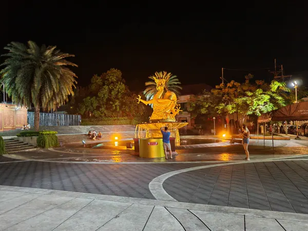 An illuminated golden dragon and palms in Phuket after dark