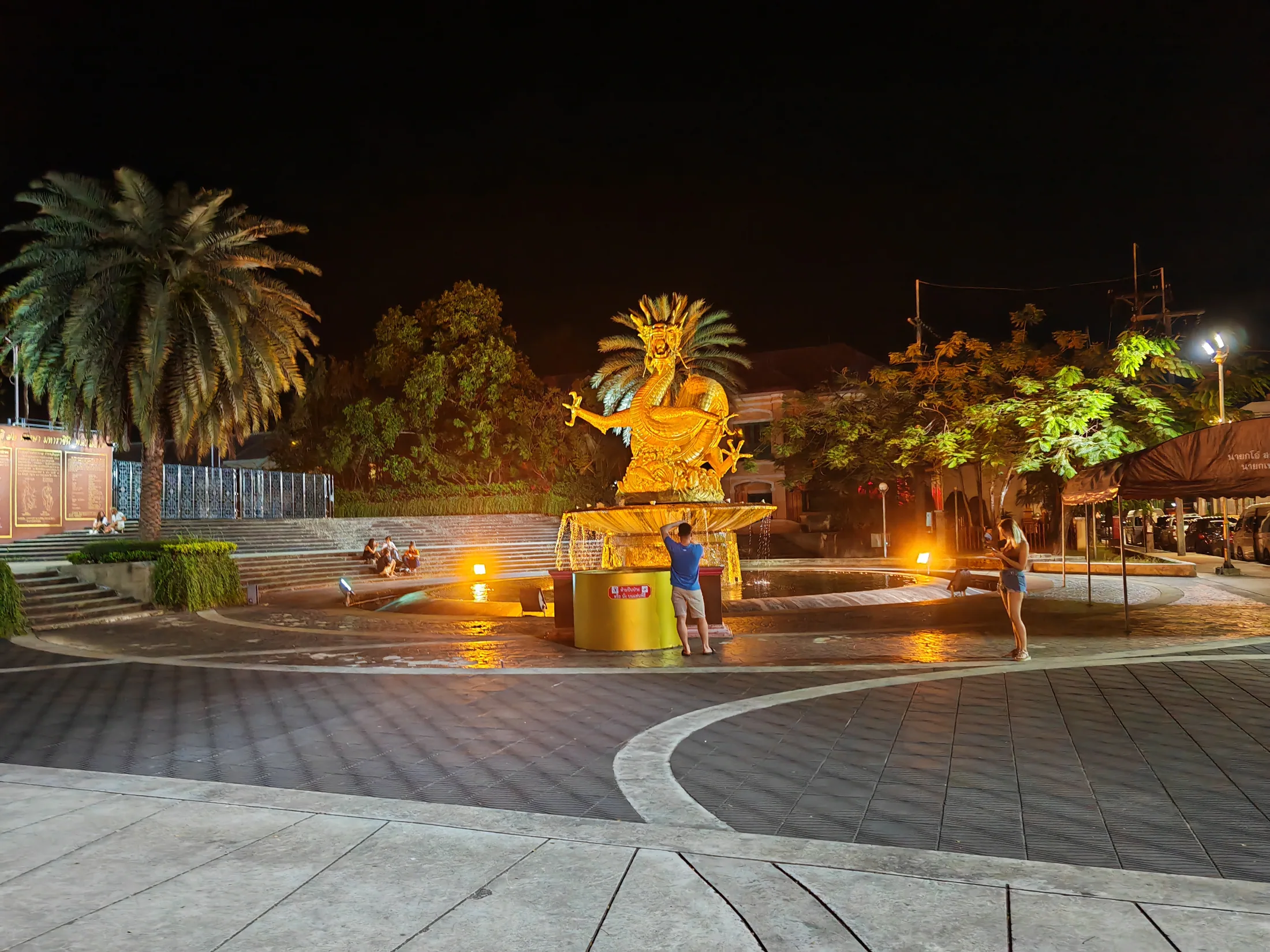 An illuminated golden dragon and palms in Phuket after dark