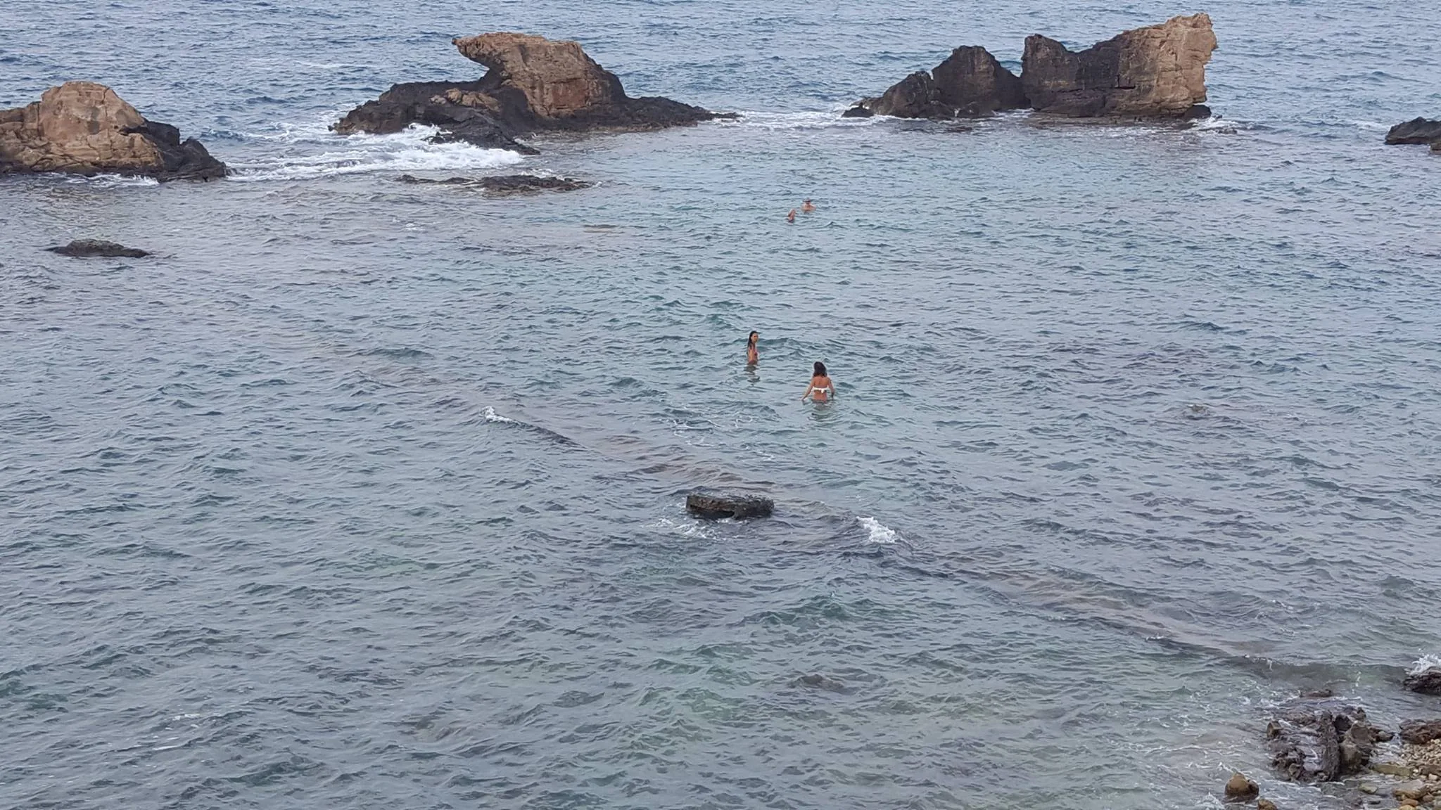 Rocky outcrops and swimmers along the Crete coast