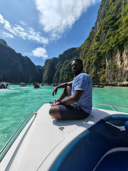 A traveller seated at the bow of a boat between limestone cliffs in Krabi