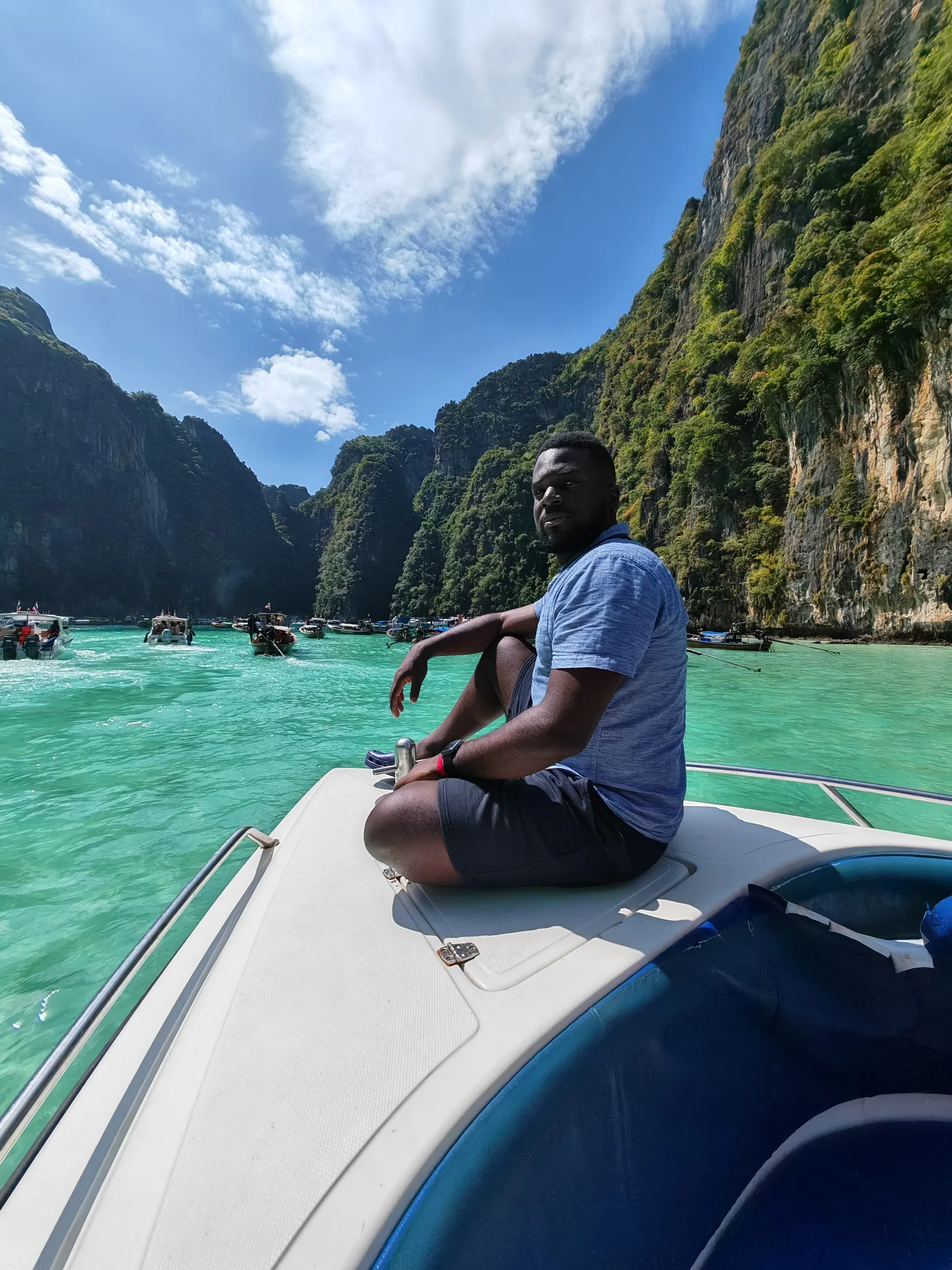 A traveller seated at the bow of a boat between limestone cliffs in Krabi