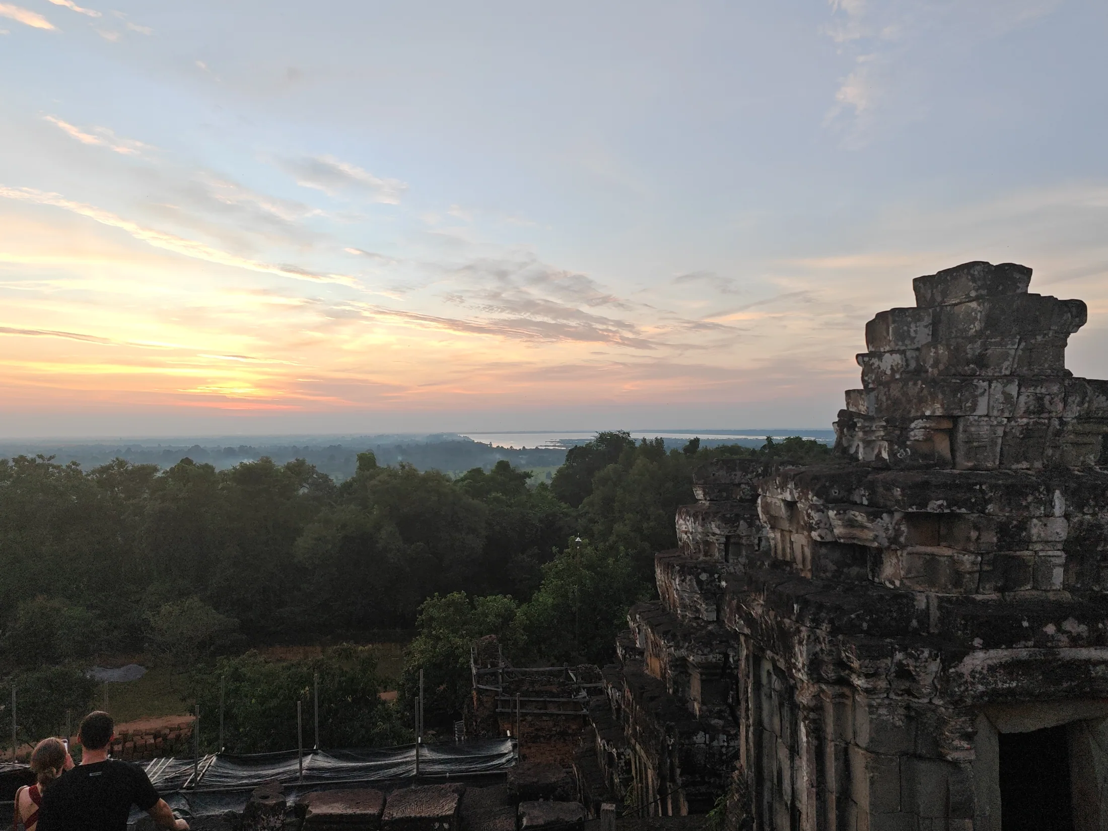 An ancient Angkor temple above the trees in warm evening light