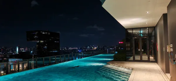 An illuminated rooftop pool overlooking Bangkok at night