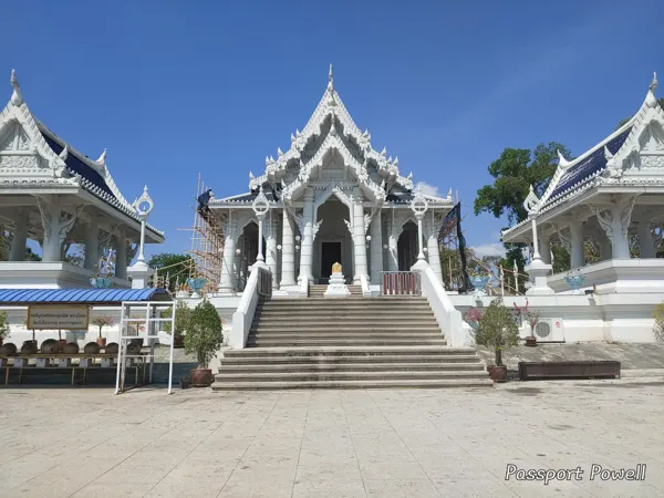 Ornate pale temple roofs and steps beneath a blue Thai sky