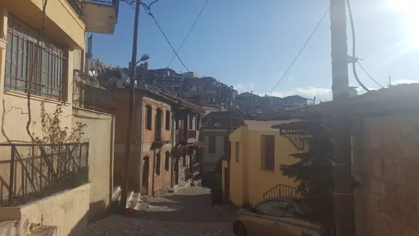 A sunlit lane descending between village buildings