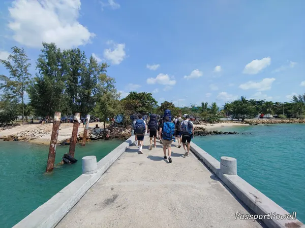 Visitors crossing a narrow pier over clear turquoise water