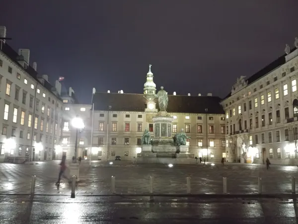 An illuminated Vienna square reflected on wet paving