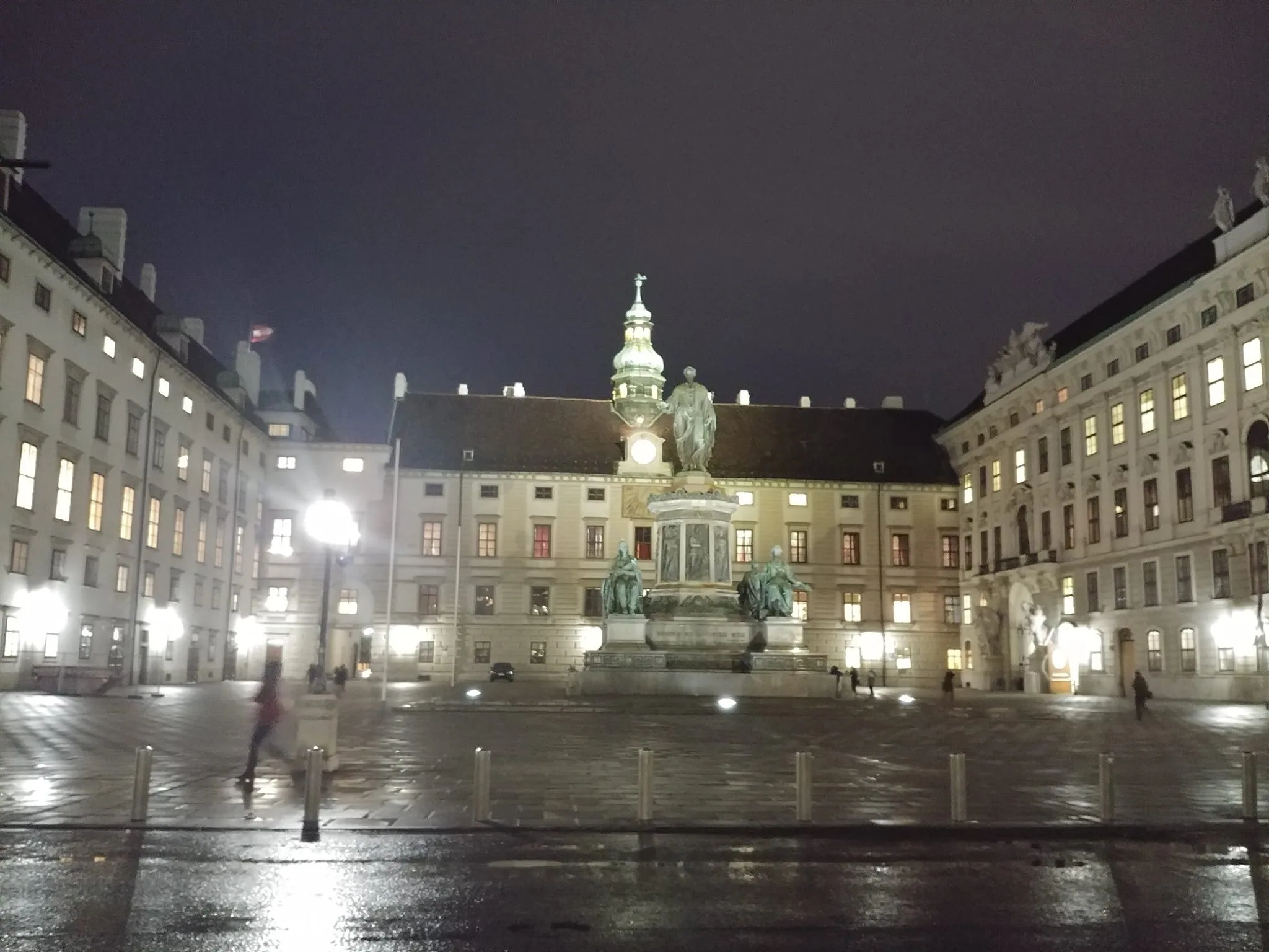 An illuminated Vienna square reflected on wet paving