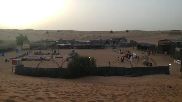 A desert camp below rolling dunes in the evening