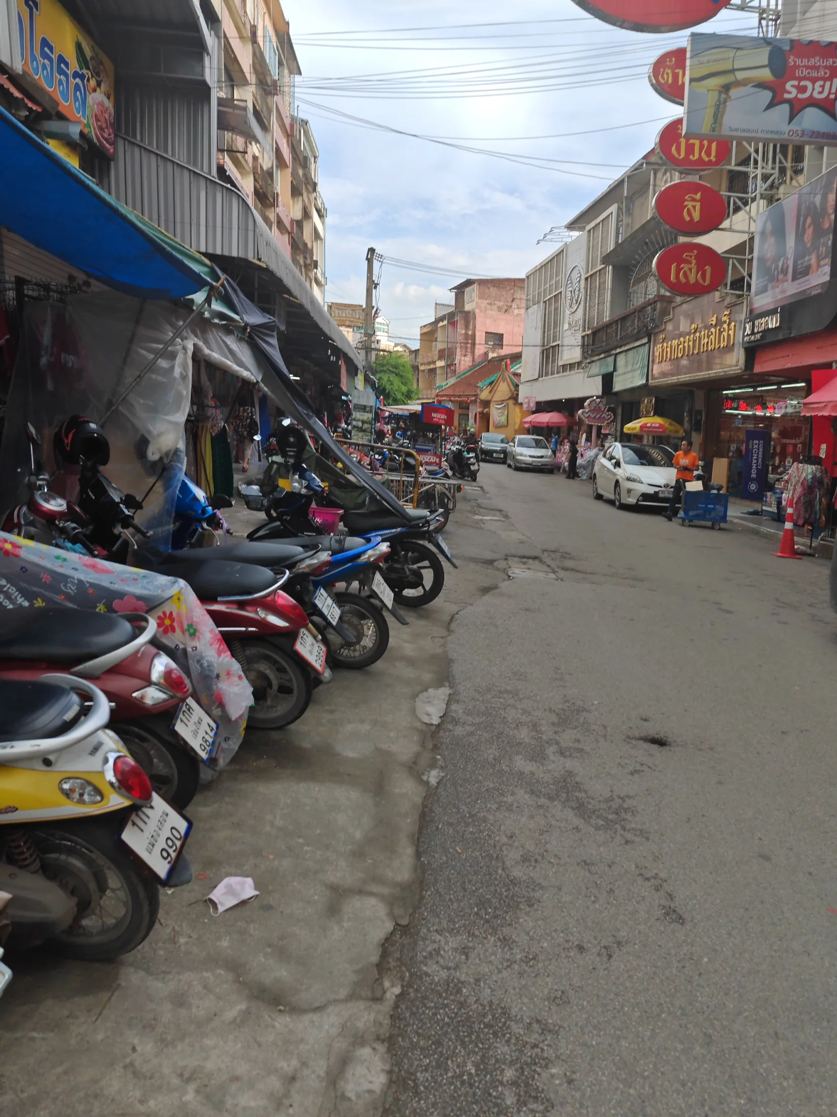Scooters and shopfronts along a Chiang Mai street
