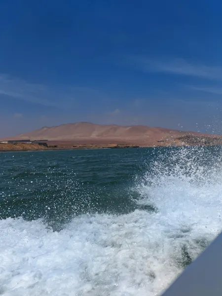 A boat’s wake beside the dry Peruvian coastline