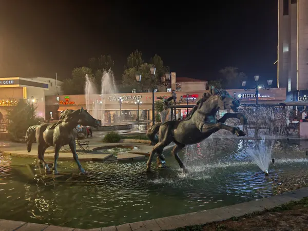 Horse sculptures and fountains lit after dark in Bishkek