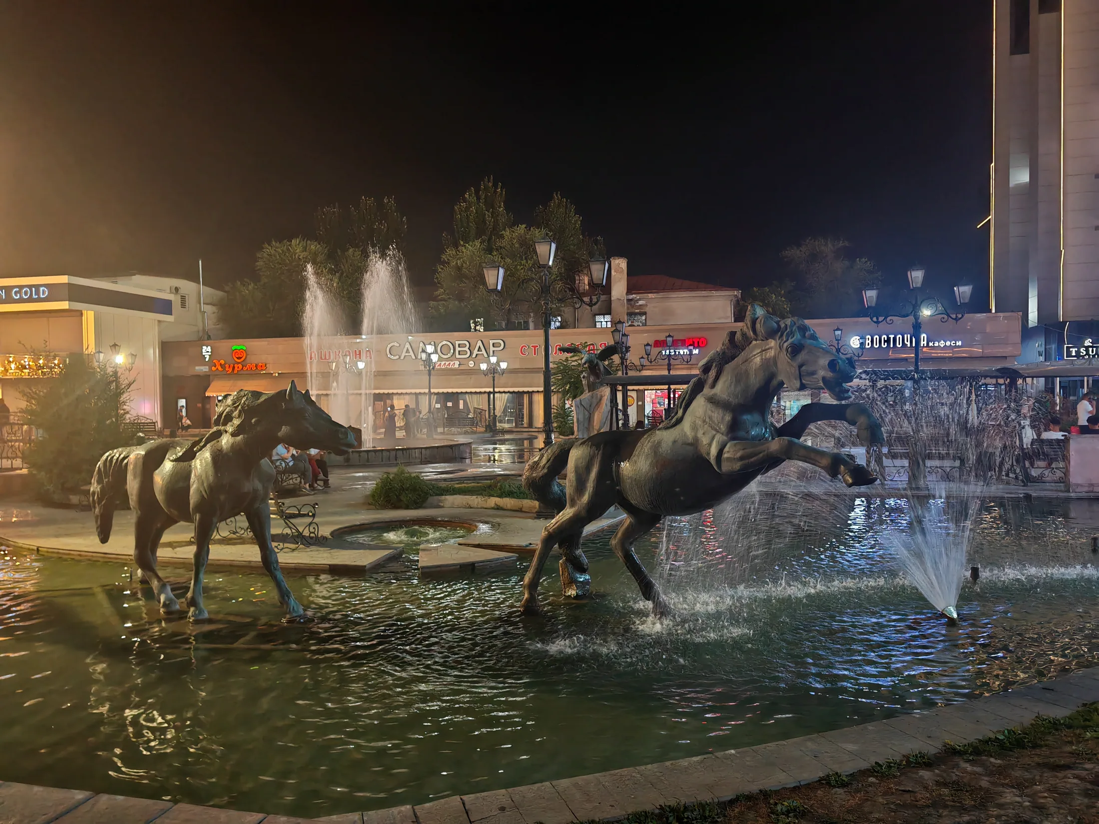 Horse sculptures and fountains lit after dark in Bishkek