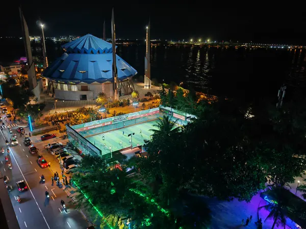 An illuminated mosque and waterfront seen from above in Malé