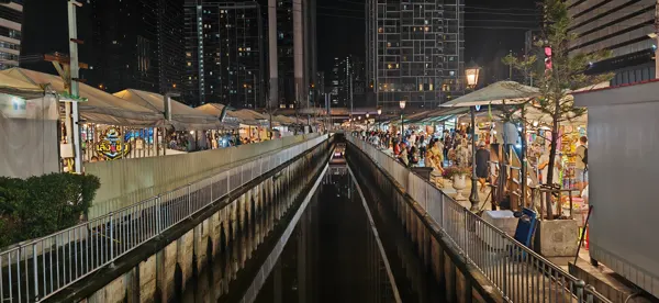 Stalls and lights beside a canal during a return visit to Bangkok