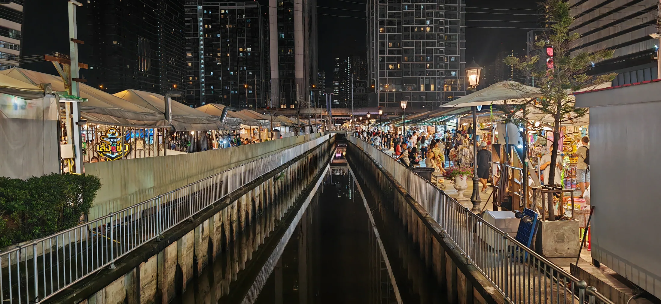 Stalls and lights beside a canal during a return visit to Bangkok