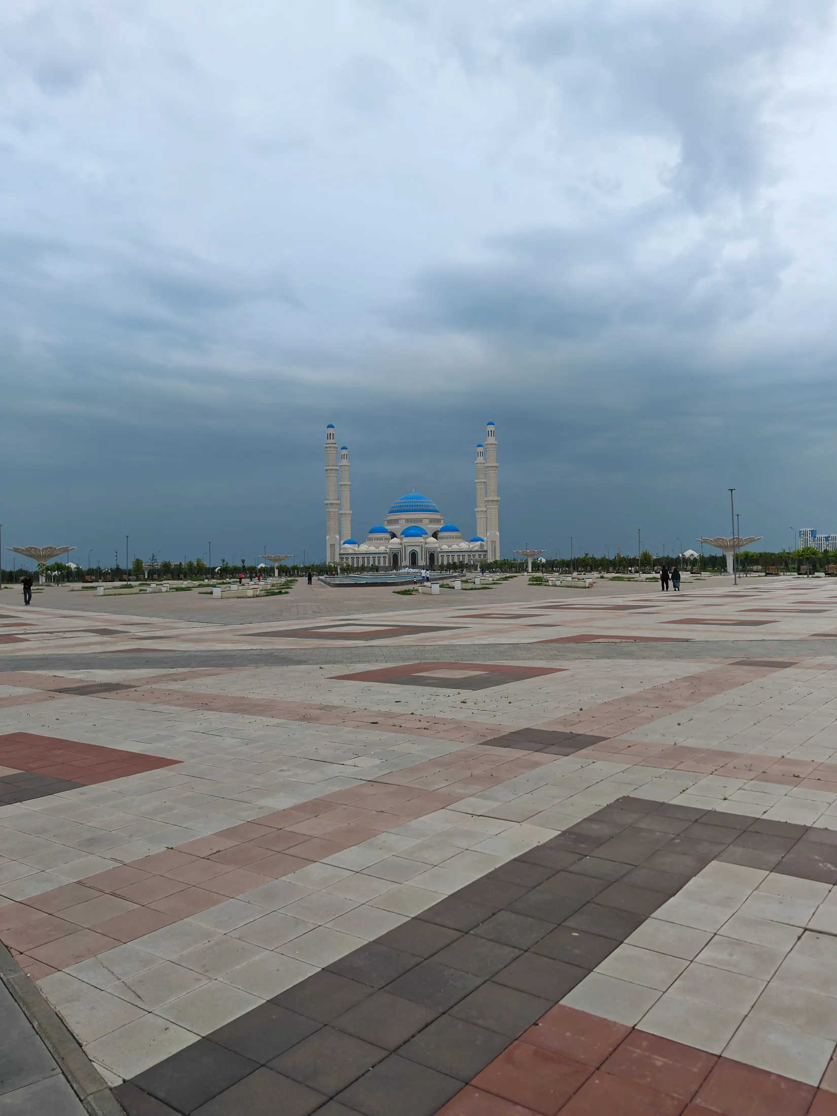 A broad paved square and mosque beneath a cloudy Astana sky