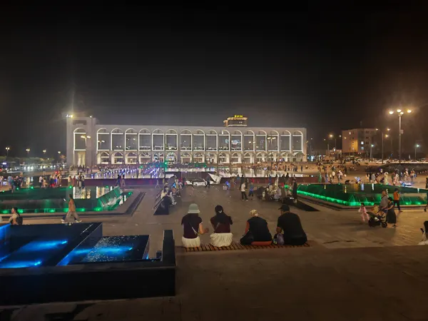 People gathering in an illuminated Bishkek square at night