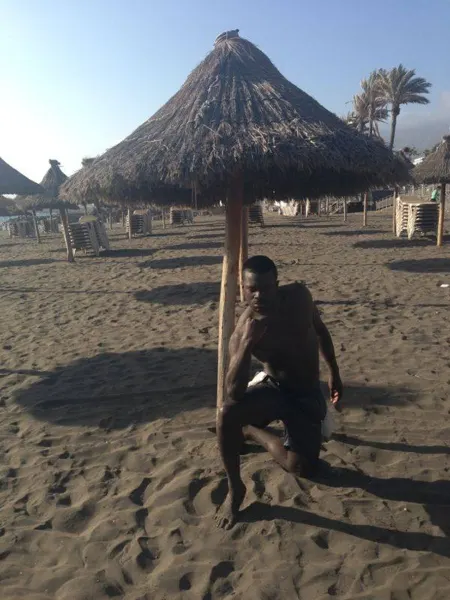 A traveller resting under a thatched beach shade
