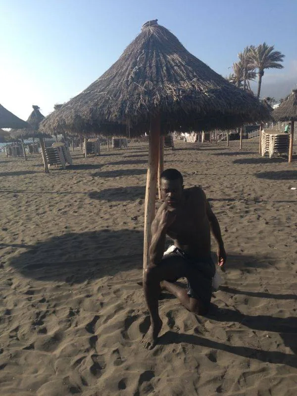 A traveller resting under a thatched beach shade