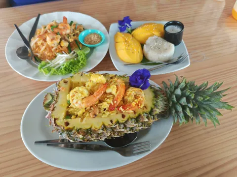 Pineapple fried rice and colourful dishes on a wooden table