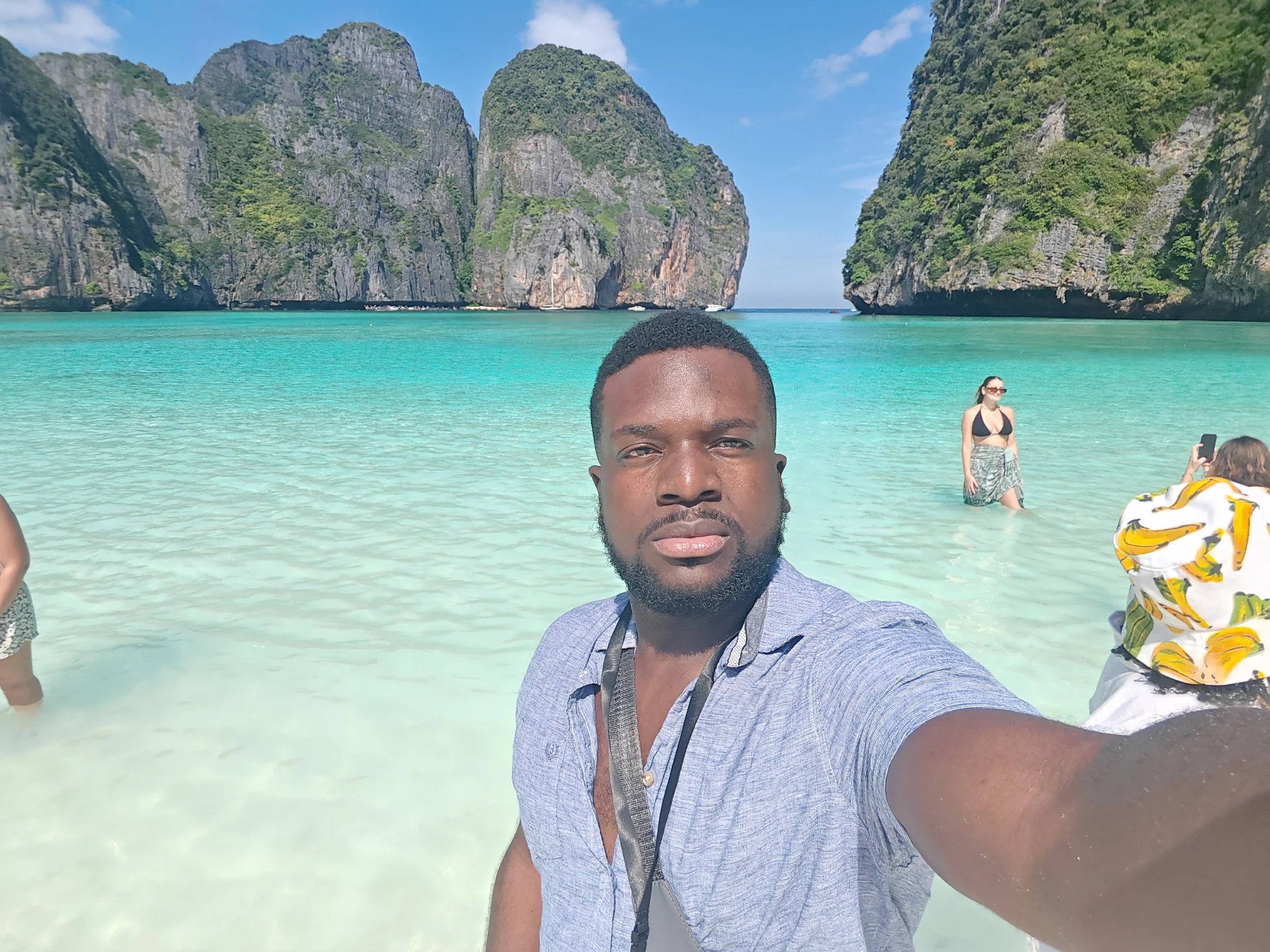 A traveller beside clear water and towering limestone cliffs