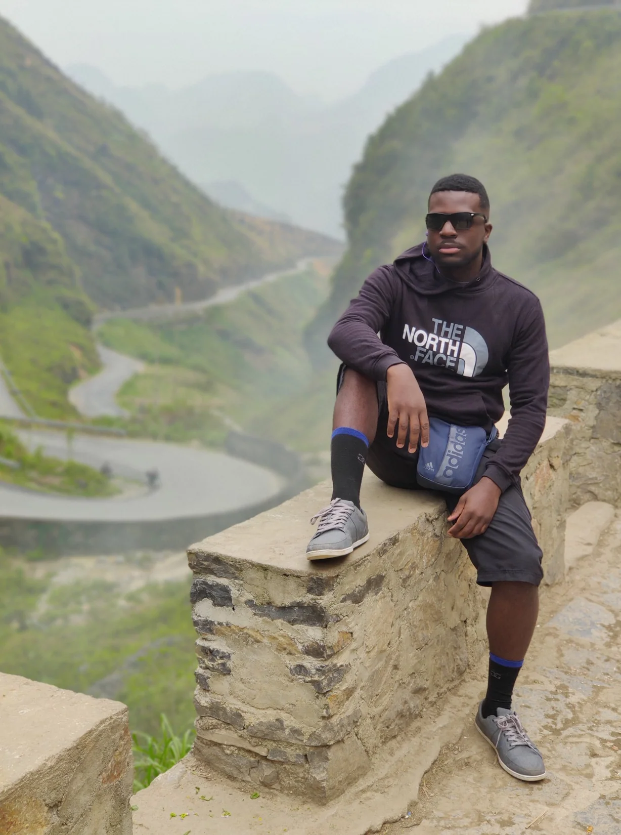 A traveller seated above a winding river between steep green mountains